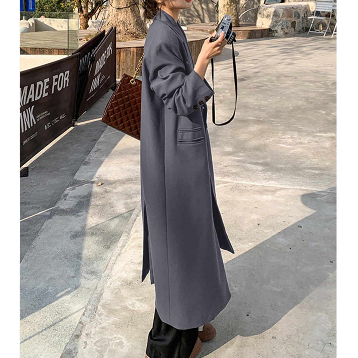 a woman in a long coat holding a camera