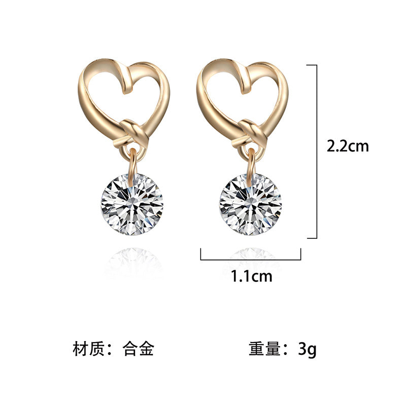 a pair of gold heart shaped earrings with a diamond