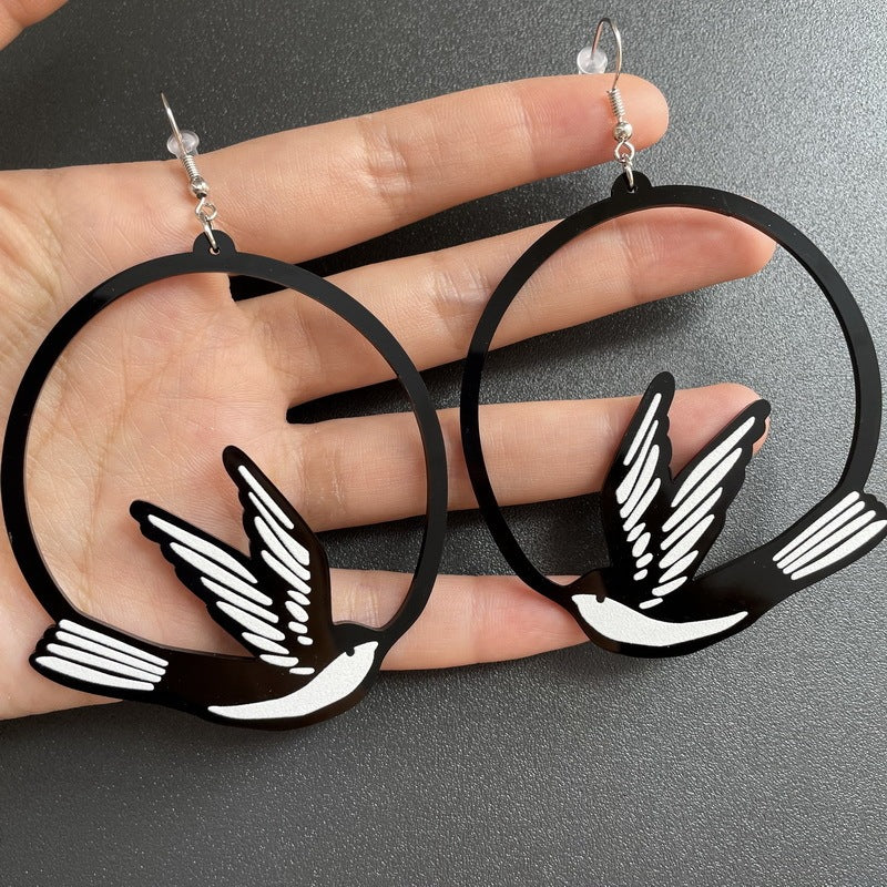 a pair of black hoop earrings with birds on them