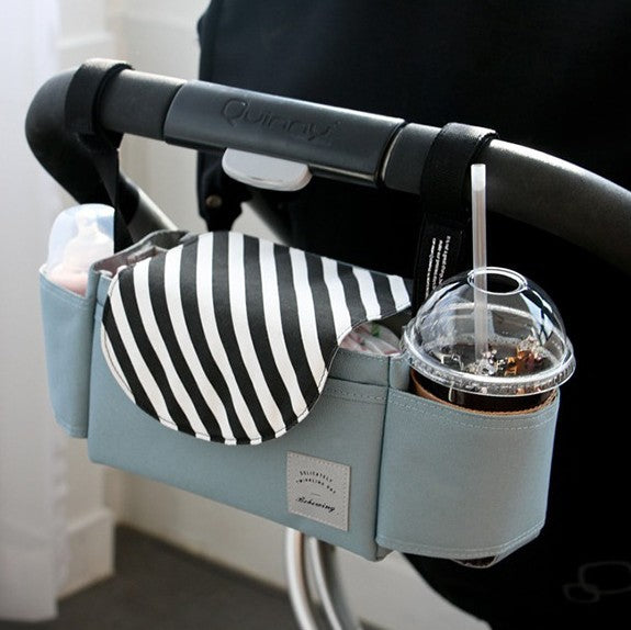 a bag with a drink and a straw on the handle of a stroller
