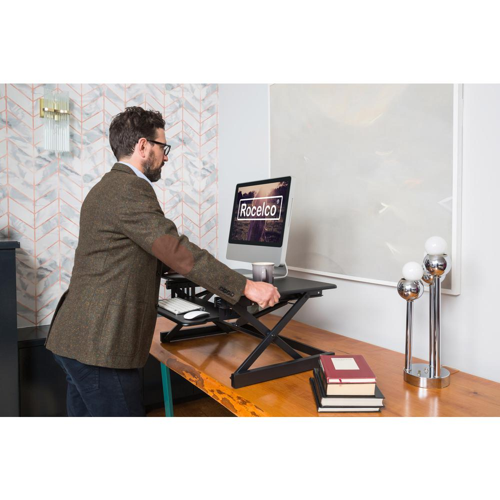 a man standing at a desk with a computer