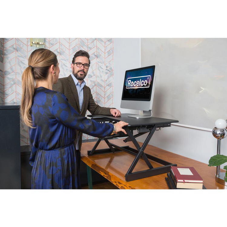 a man and woman standing next to a computer