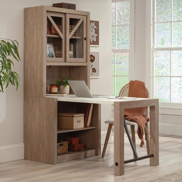 a desk with a laptop and a chair in a room with windows