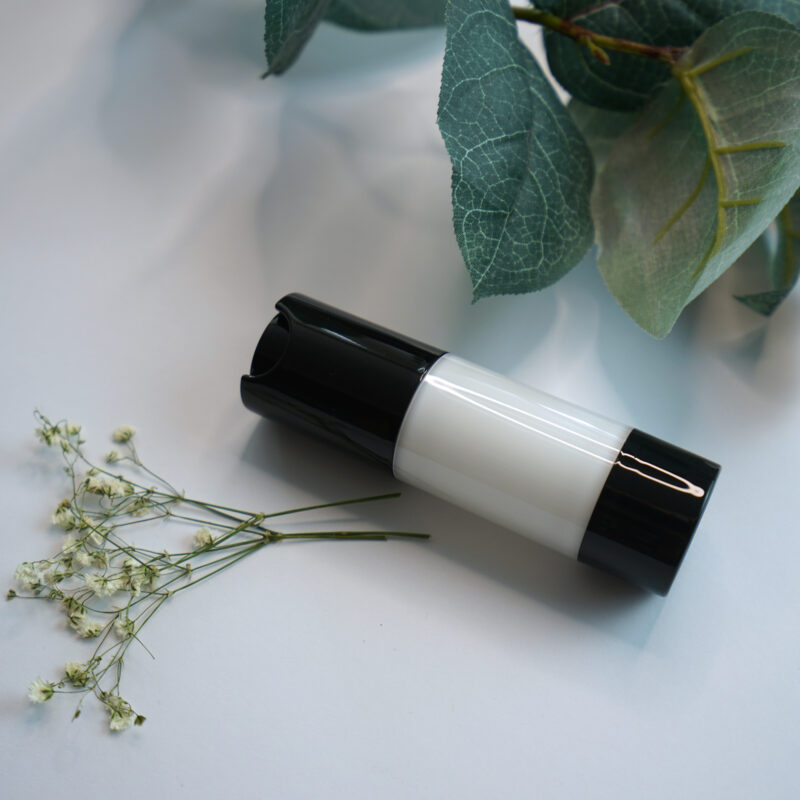 a small bottle of cream next to a plant