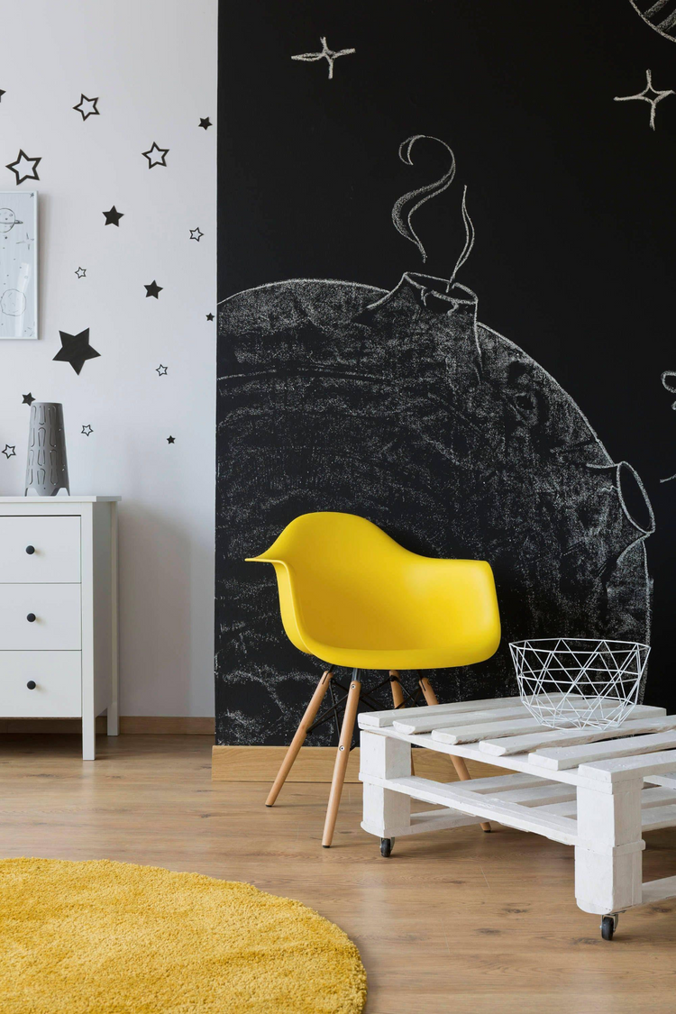 a yellow chair in a room with a black wall and white furniture