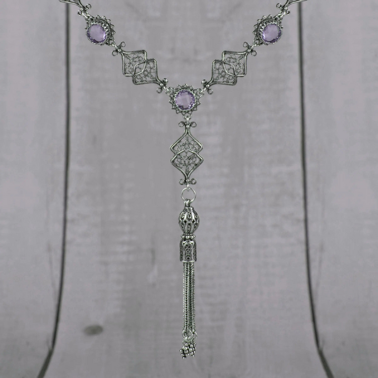 a silver necklace with purple stones