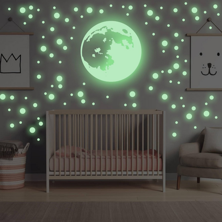 a crib with a green moon and a chair