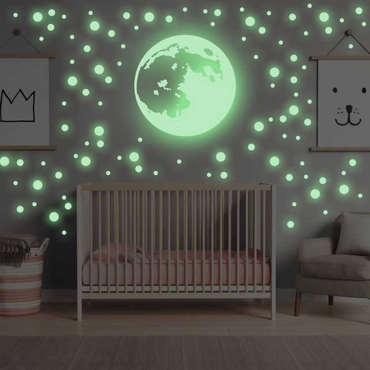 a crib with a green moon and a chair