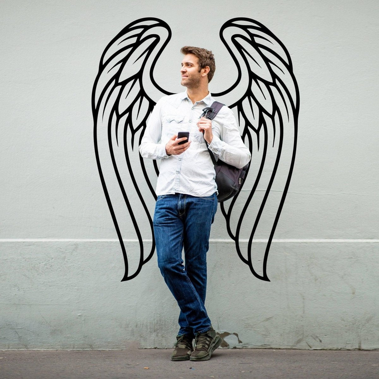 a man standing in front of a wall with wings drawn on it