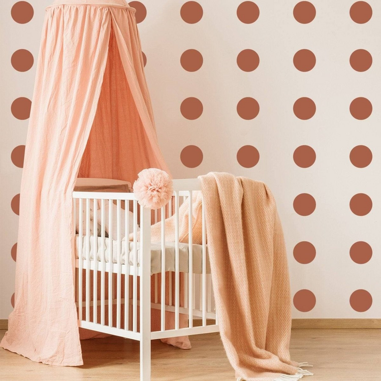 a crib with a canopy and blanket in a room with polka dots