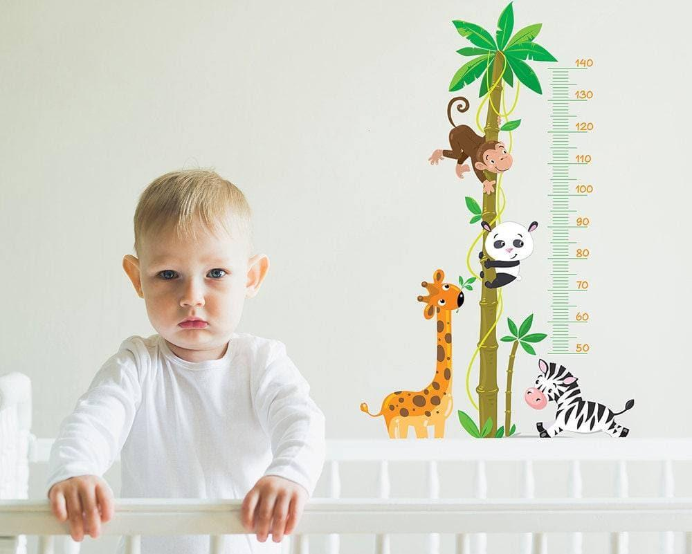 a child standing in a crib with animals on the wall