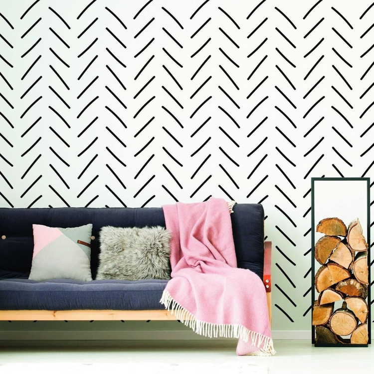 a couch with pillows and a pink blanket in front of a wall with black lines