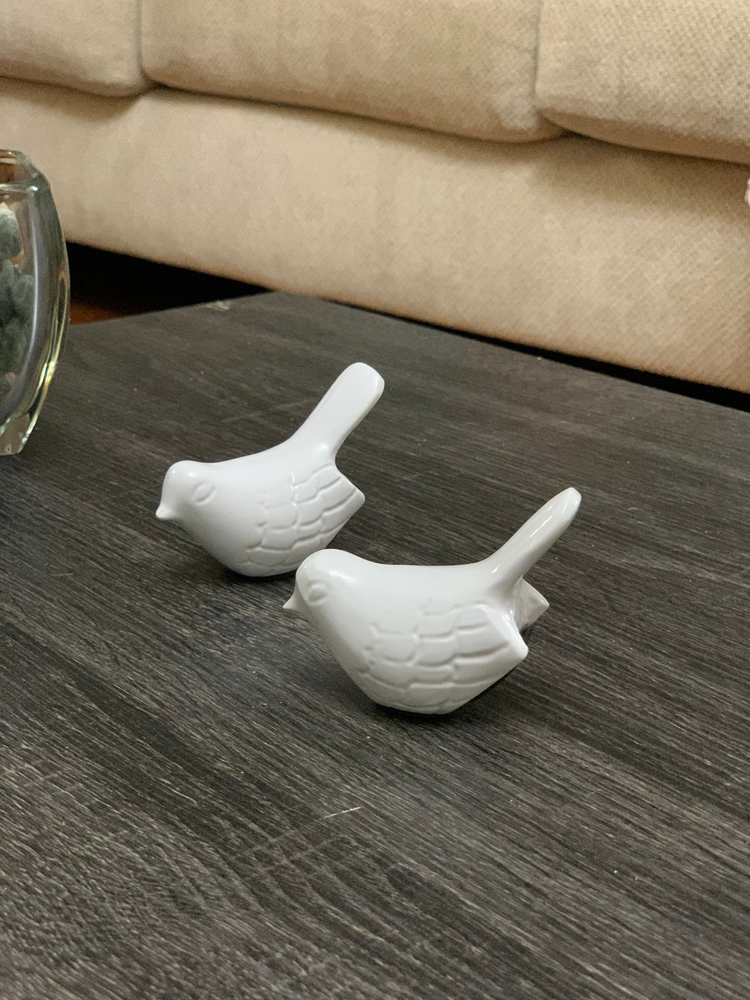 two white ceramic birds on a table