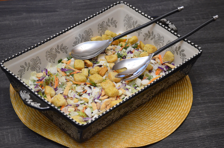 a bowl of salad with a pair of spoons