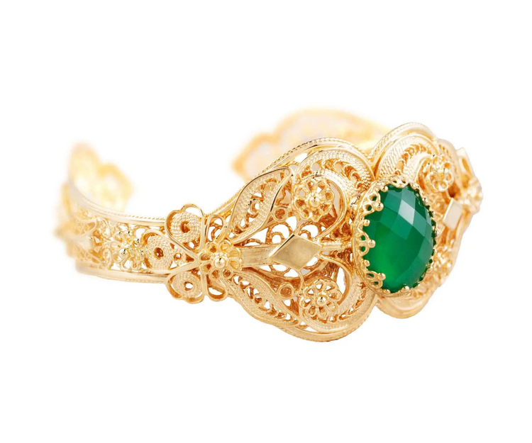 a gold bracelet with a green stone