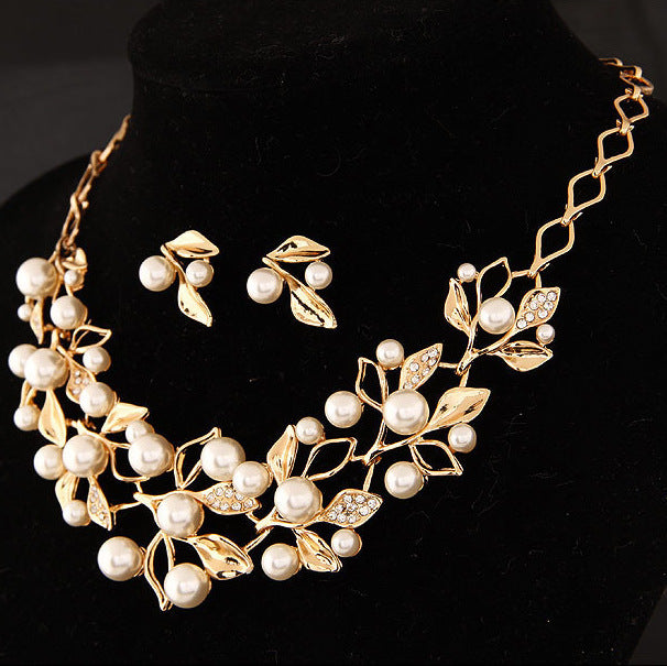 a gold necklace and earrings on a black mannequin