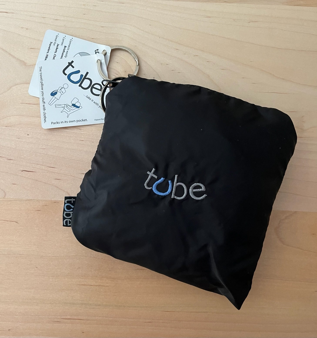 a black bag with a keychain on a wood surface