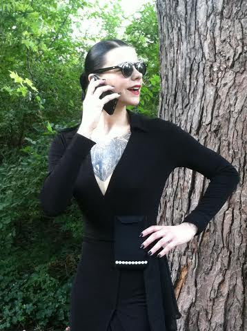 a woman in a black dress talking on a cell phone