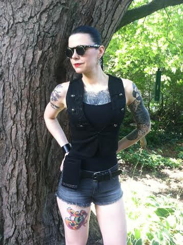 a woman with tattoos and a vest