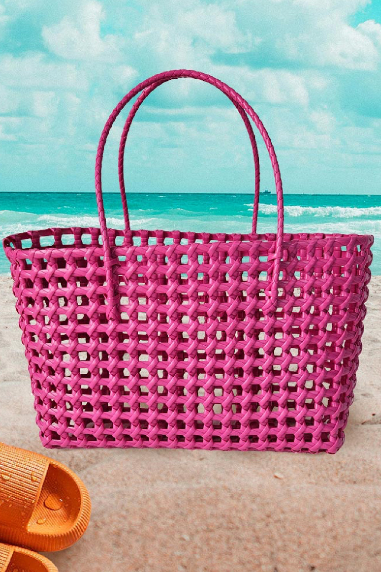 a pink woven bag on a beach