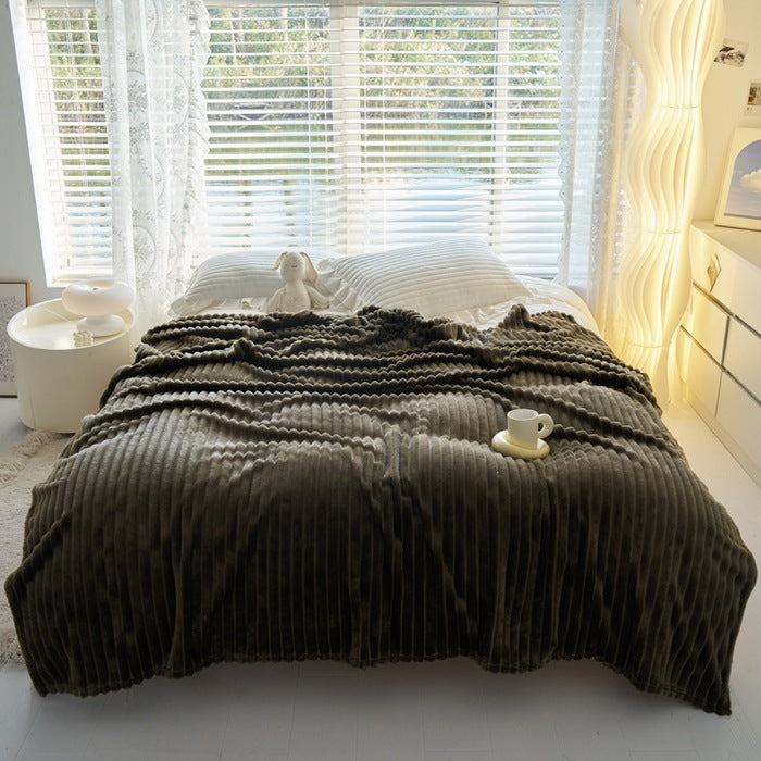 a bed with a blanket and a cup on it