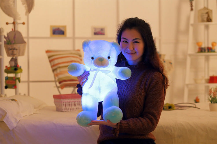 a woman holding a light up teddy bear