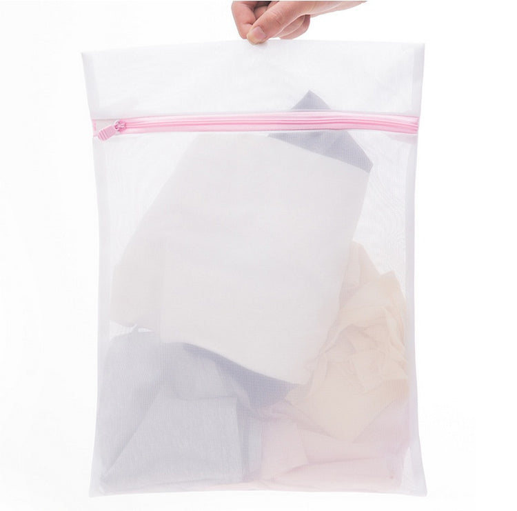 a hand holding a white bag with clothes in it