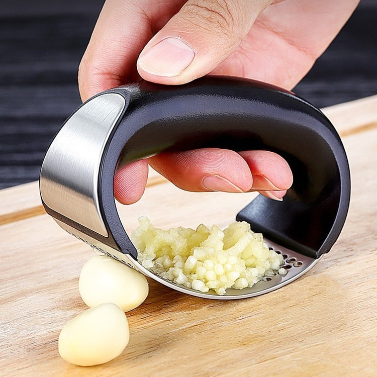 a hand holding a garlic press