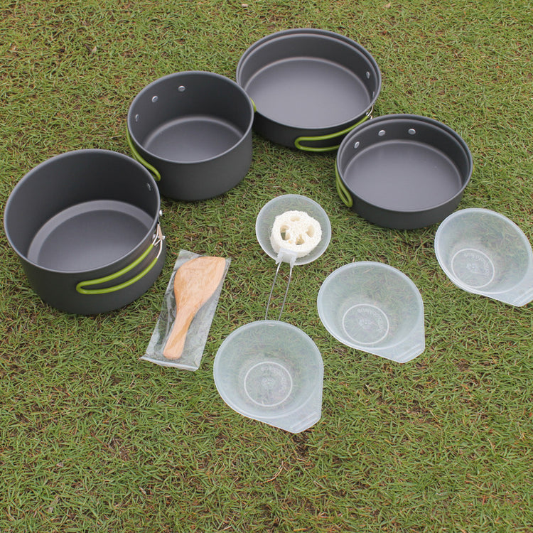 a group of camping pots and bowls on grass