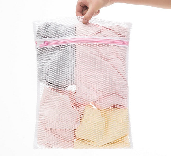 a hand holding a mesh bag of clothes