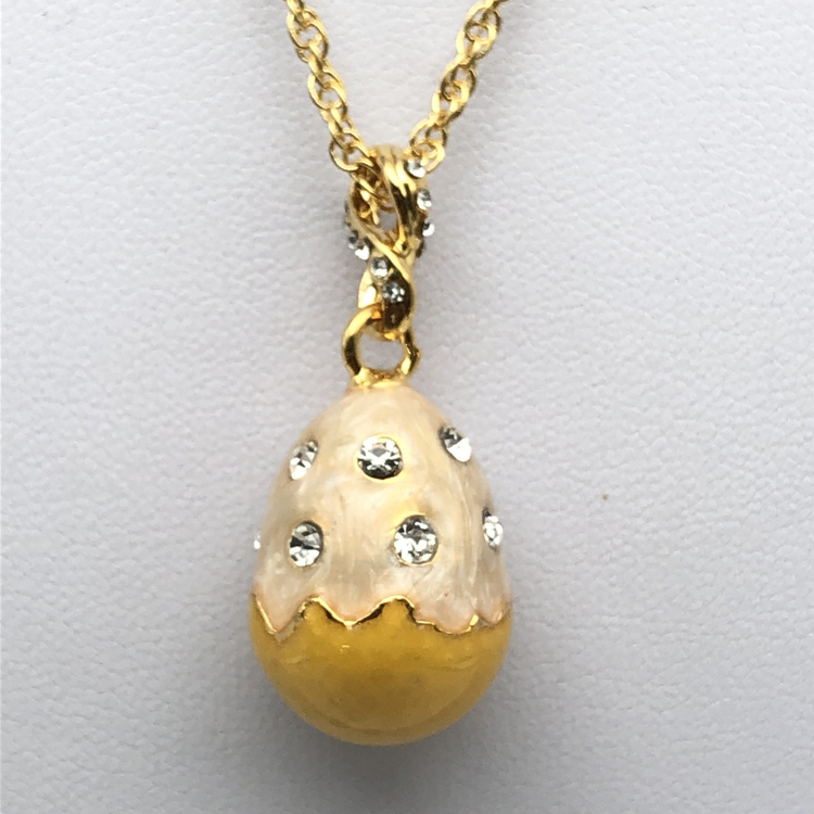 a gold and white egg pendant with diamonds