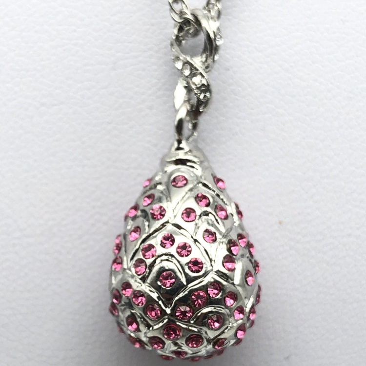 a silver pendant with pink crystals