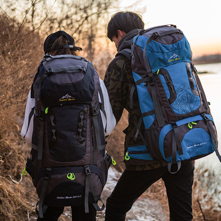 two people with backpacks walking by a body of water