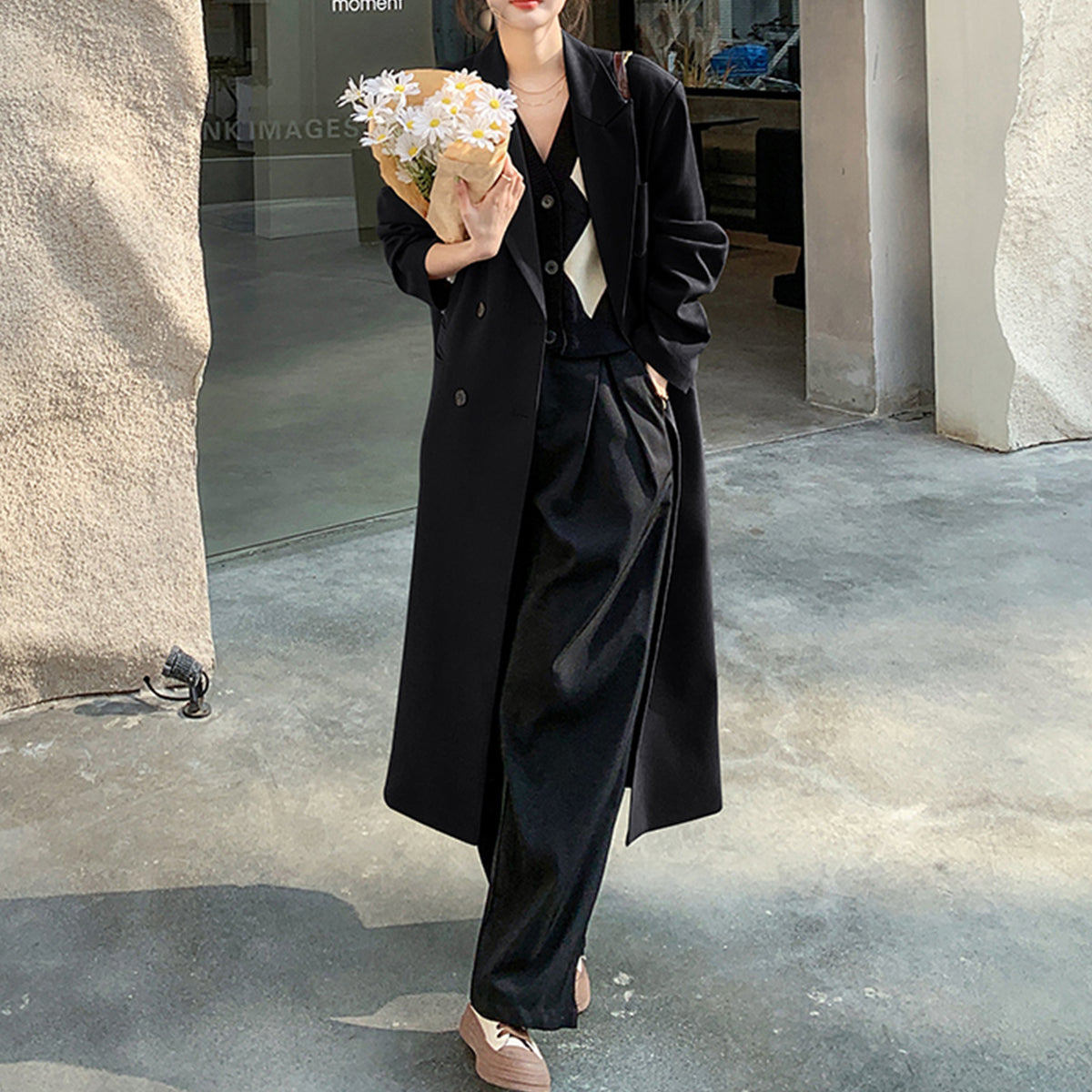 a woman in a black coat holding a bouquet of flowers
