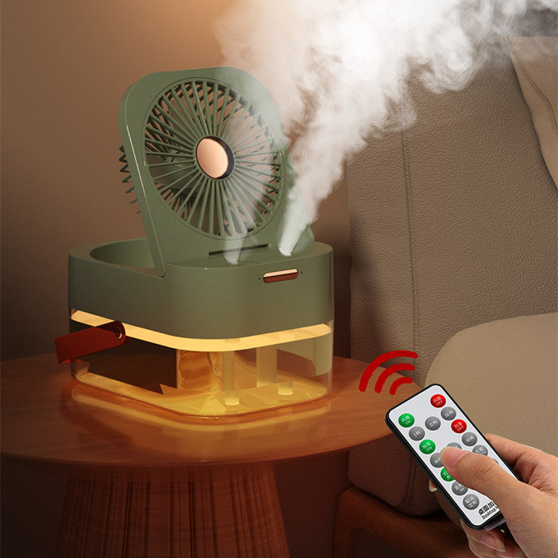 a hand holding a remote control and a fan on a table