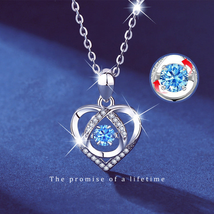 a silver necklace with a blue gem in the shape of a heart