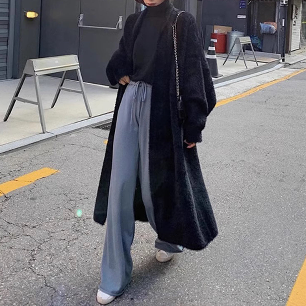a woman wearing a black coat and grey pants