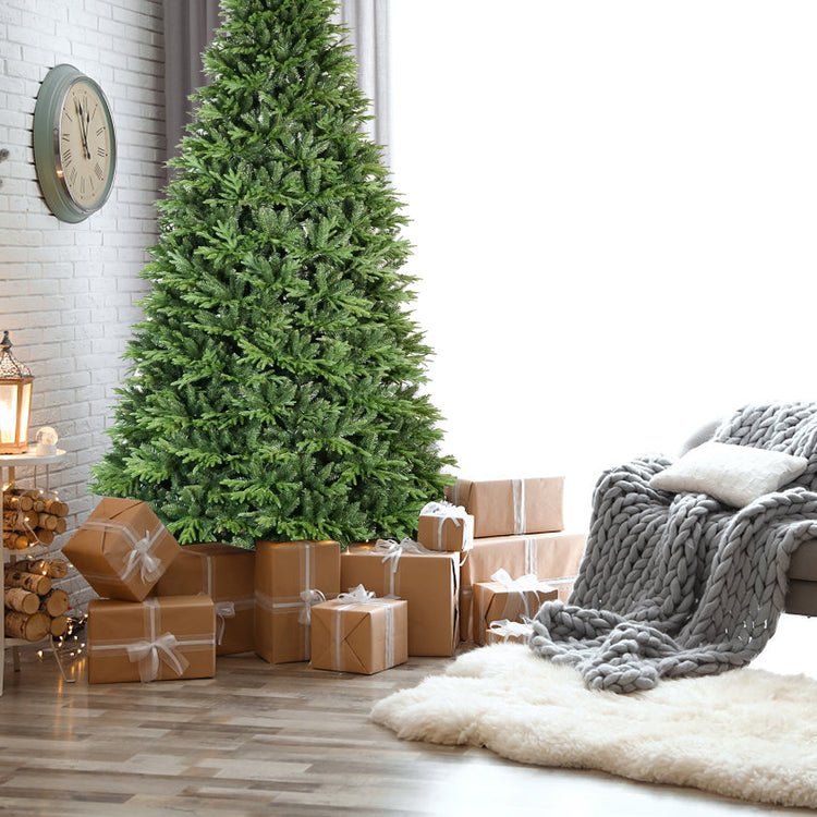 a christmas tree with presents in front of a white brick wall