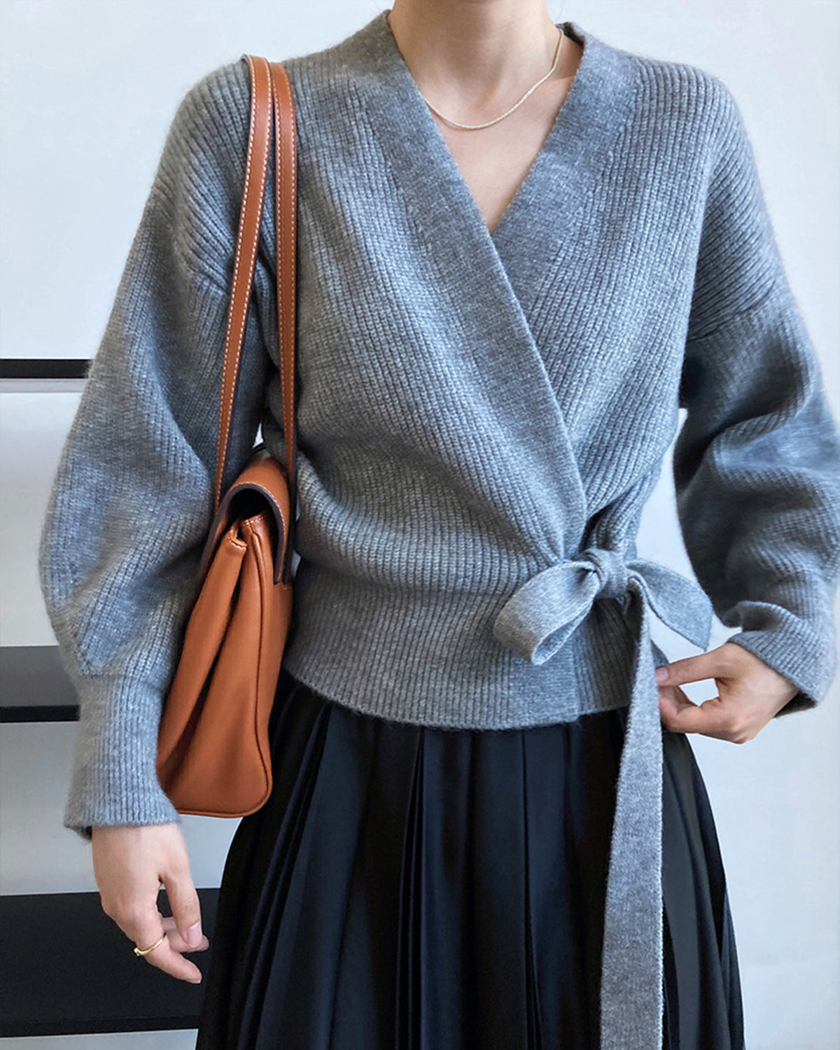 a woman wearing a grey sweater and a black skirt
