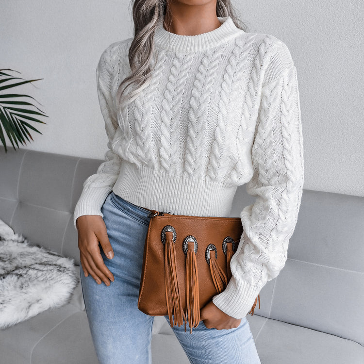 a woman in a white sweater holding a brown purse