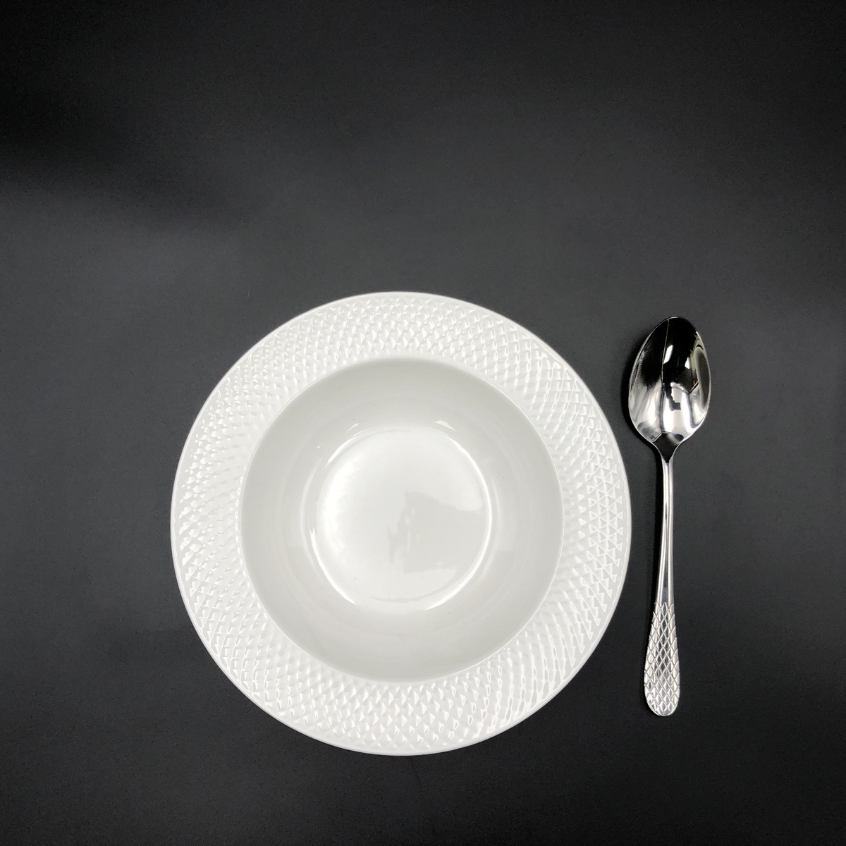 a white plate and spoon on a black surface