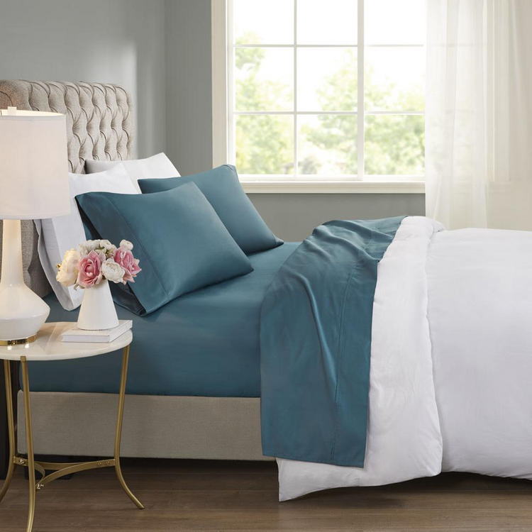a bed with blue sheets and a lamp