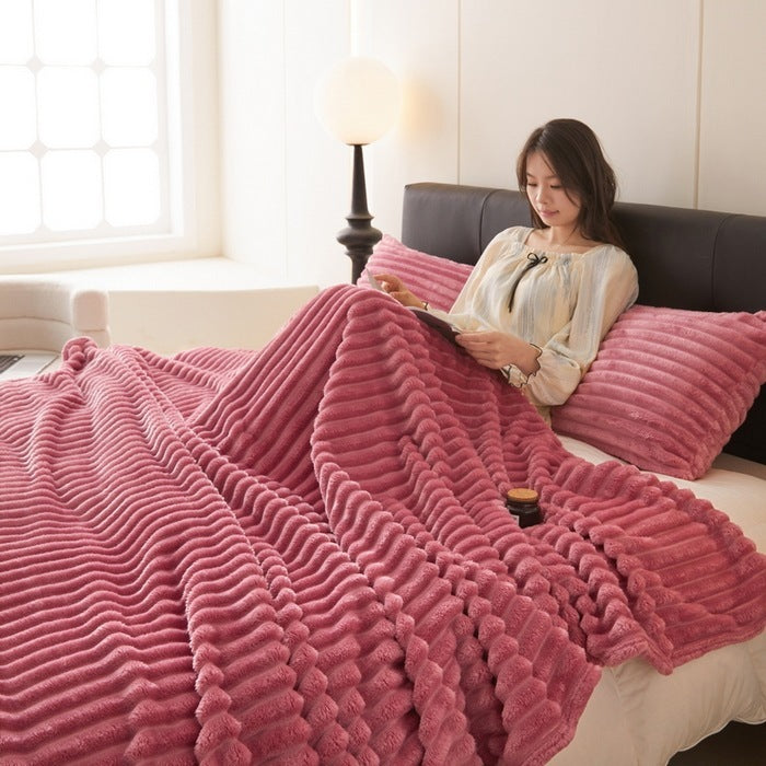 a woman lying in bed with a pink blanket