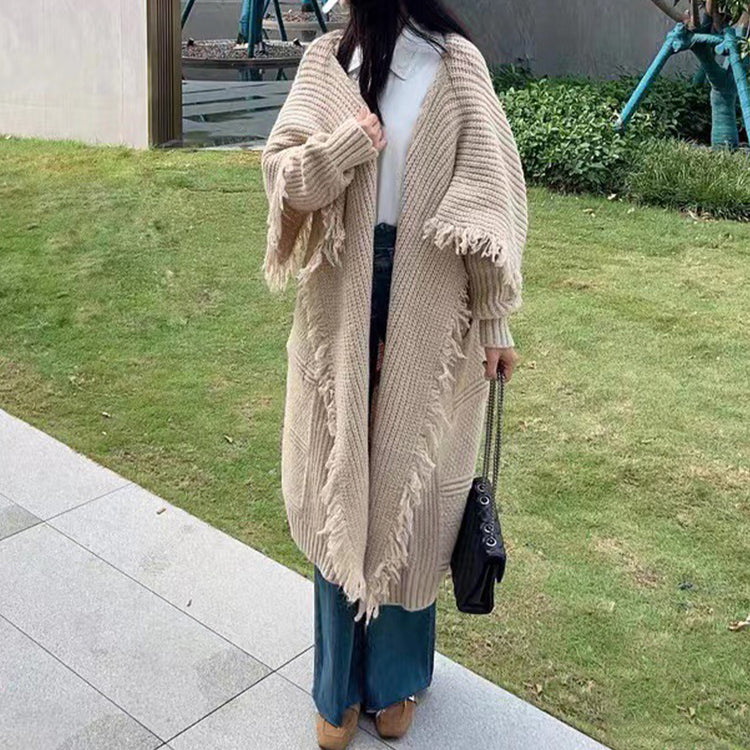 a woman wearing a long cardigan and a hat