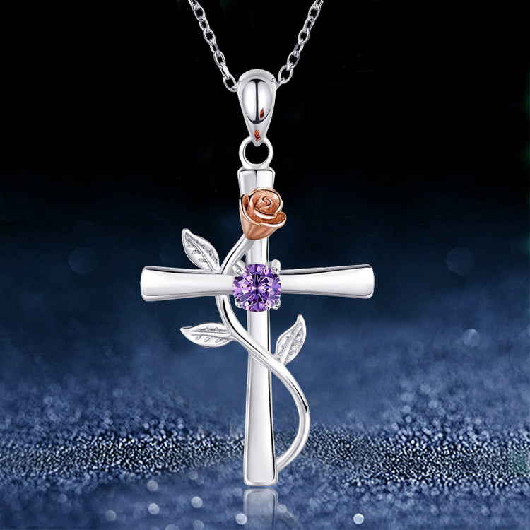 a silver cross with a purple flower and a purple stone on a chain