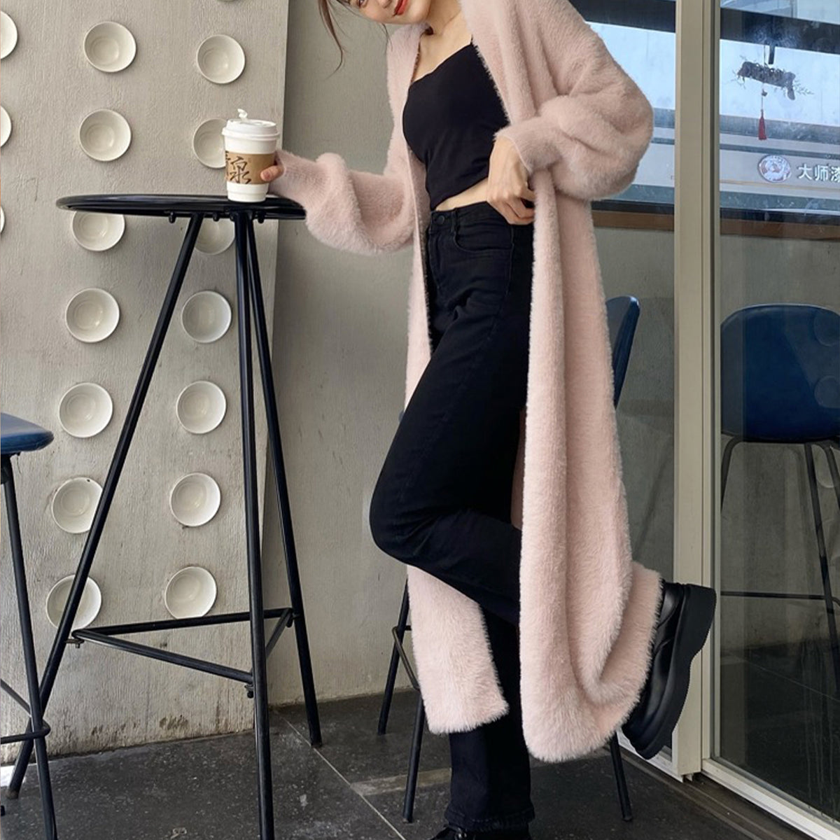 a woman in a pink coat holding a coffee cup