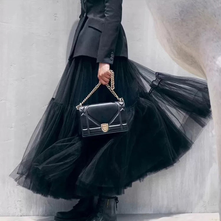 a person wearing a black tulle skirt and a black purse