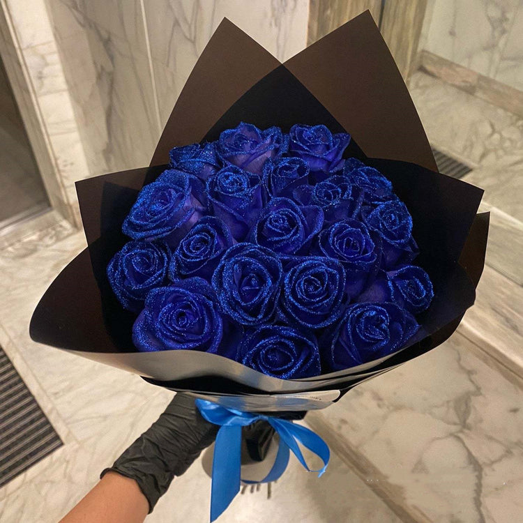 a hand holding a bouquet of blue roses