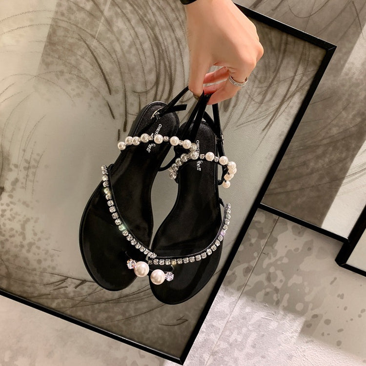 a hand holding a pair of sandals
