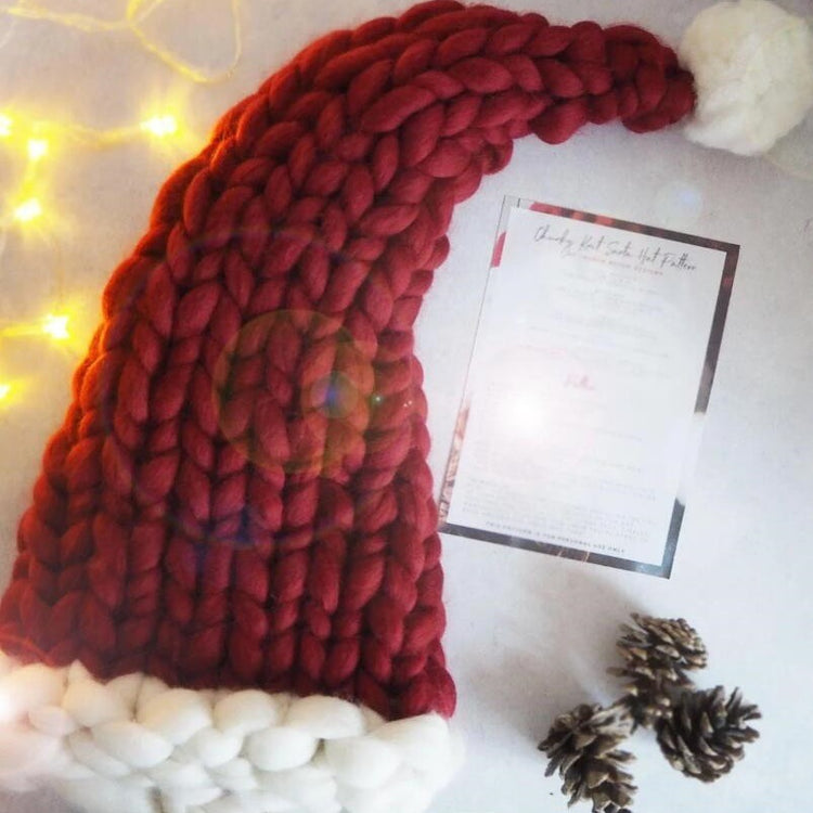 a red and white knit hat with a white and white pompom on a white surface
